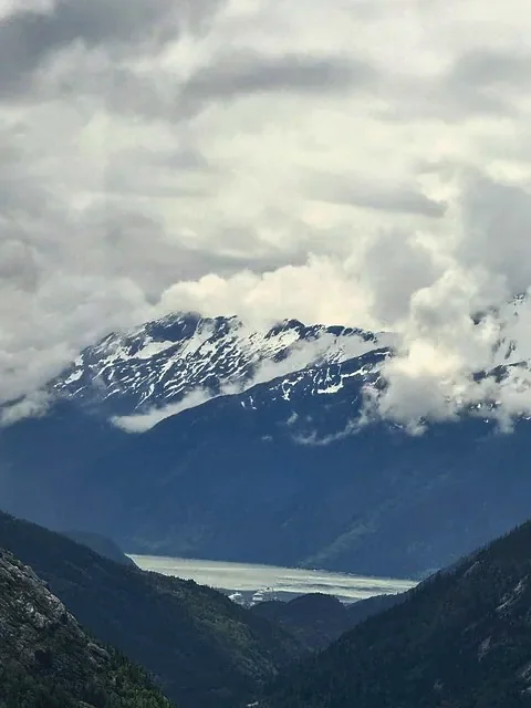 A glacier valley below snow peaks and heavy Alaskan cloud