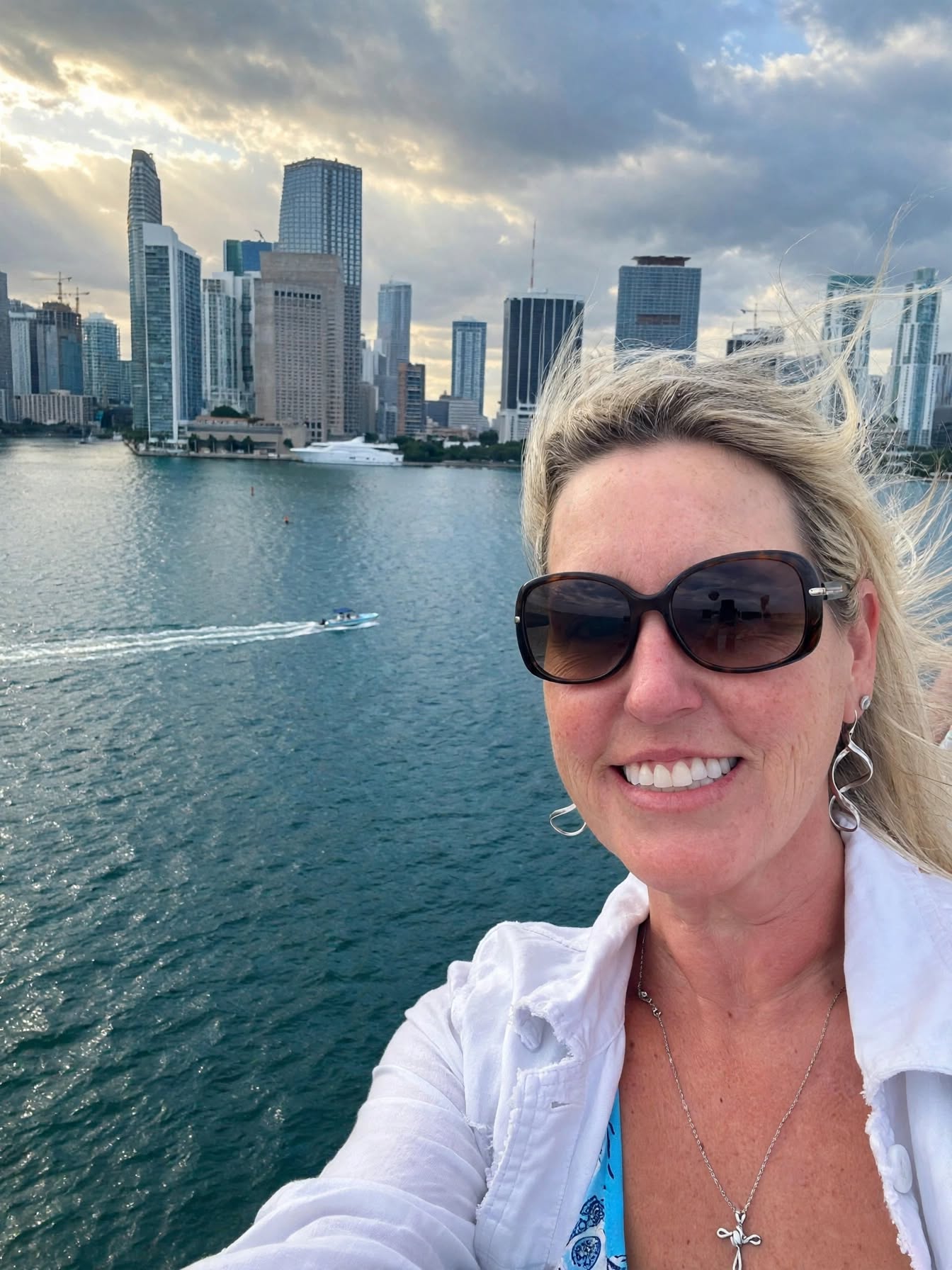 Jennifer Gregg taking a selfie on the water with the Miami skyline behind her
